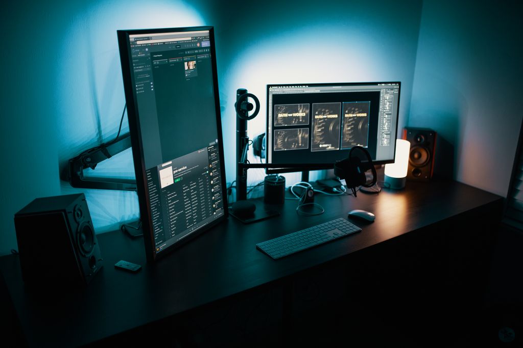 A contemporary office desk featuring a dual monitor setup with monitor arms