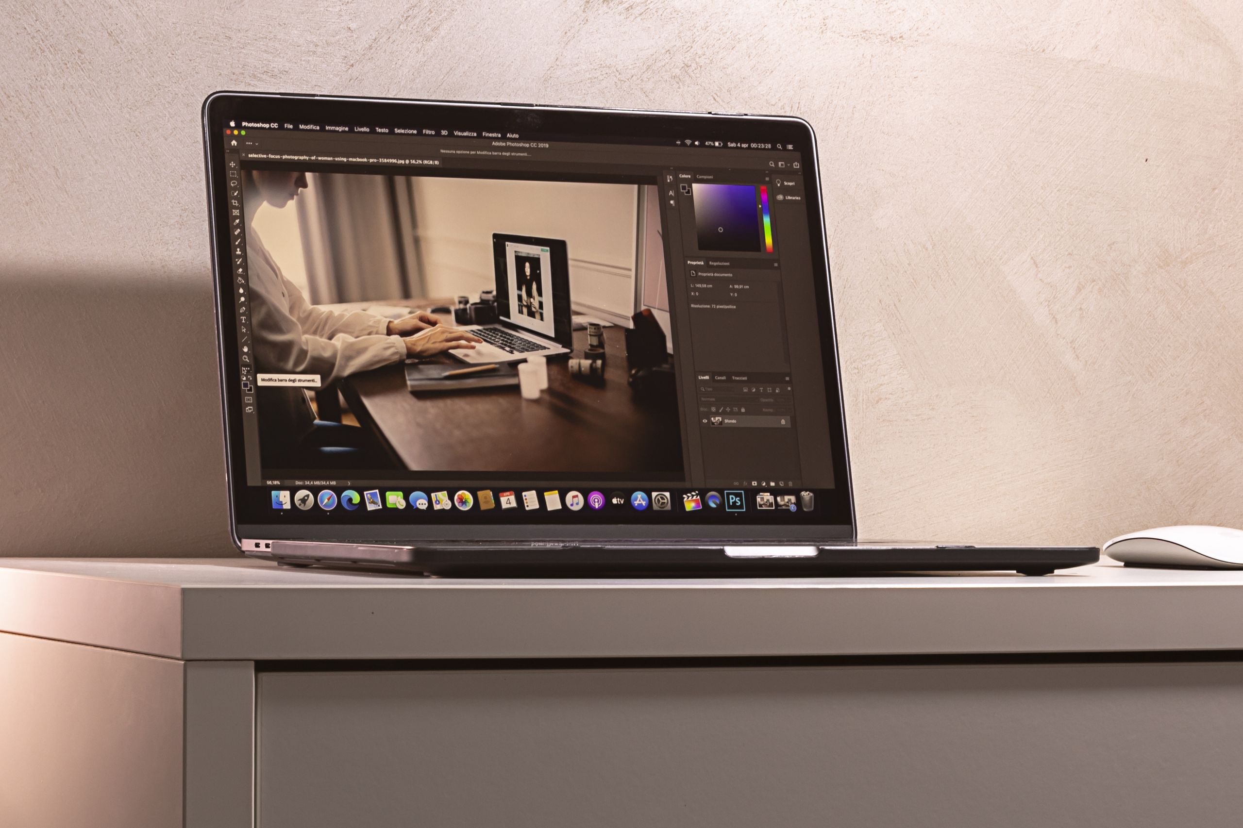 A Macbook displaying a photo editing software interface on a clean, modern desk setup.